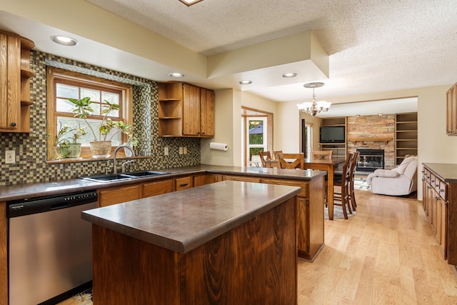 kitchen with light hardwood / wood-style flooring, sink, stainless steel dishwasher, backsplash, and a center island