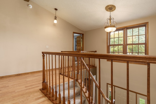 staircase featuring wood-type flooring, a textured ceiling, and vaulted ceiling