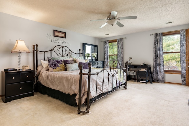 bedroom with ceiling fan, light colored carpet, a textured ceiling, and multiple windows