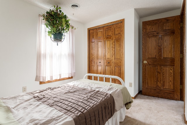 carpeted bedroom with a closet and a textured ceiling