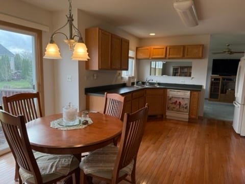 kitchen with light wood-type flooring, hanging light fixtures, sink, white appliances, and ceiling fan with notable chandelier