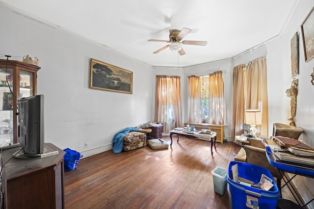 sitting room with ceiling fan, ornamental molding, and dark wood-type flooring