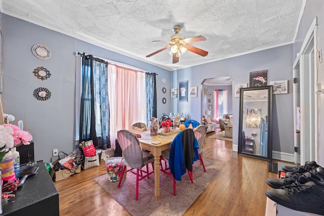 dining space featuring ceiling fan, crown molding, hardwood / wood-style flooring, and a textured ceiling