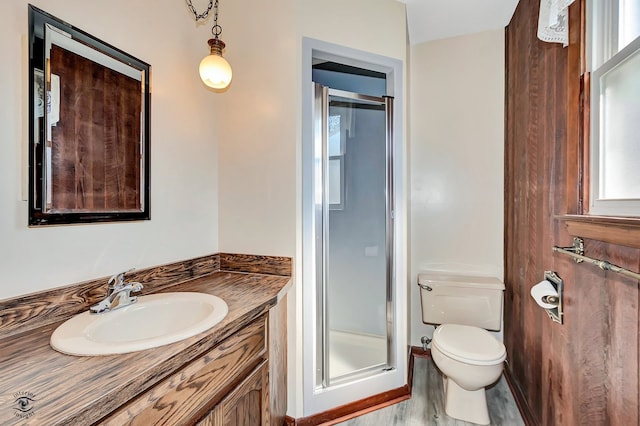 bathroom with walk in shower, hardwood / wood-style floors, vanity, and toilet