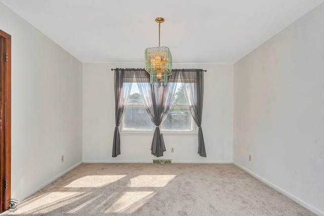 spare room featuring carpet floors and a notable chandelier