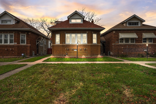 bungalow-style house featuring a yard and central AC unit