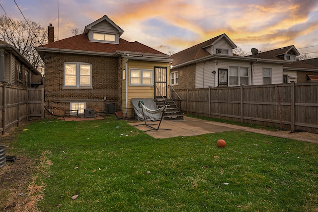 back house at dusk featuring a patio area and a yard