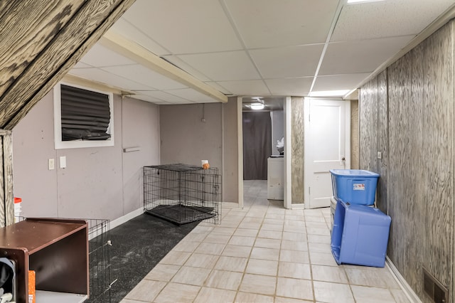 basement featuring a paneled ceiling and light tile patterned floors