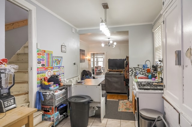 kitchen with white cabinets, light tile patterned floors, a chandelier, ornamental molding, and sink