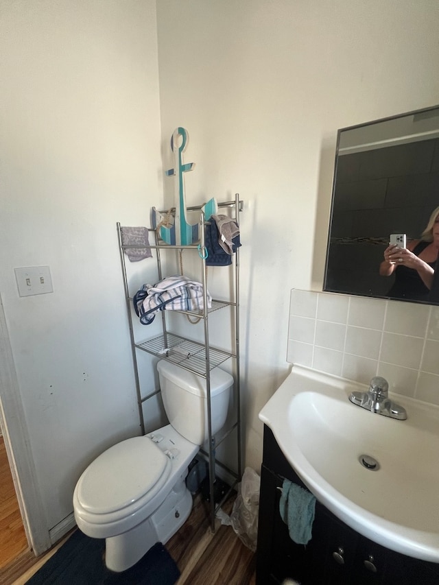 bathroom with decorative backsplash, hardwood / wood-style floors, vanity, and toilet