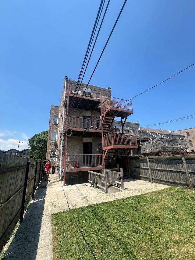 rear view of property with a wooden deck, a lawn, and a patio area