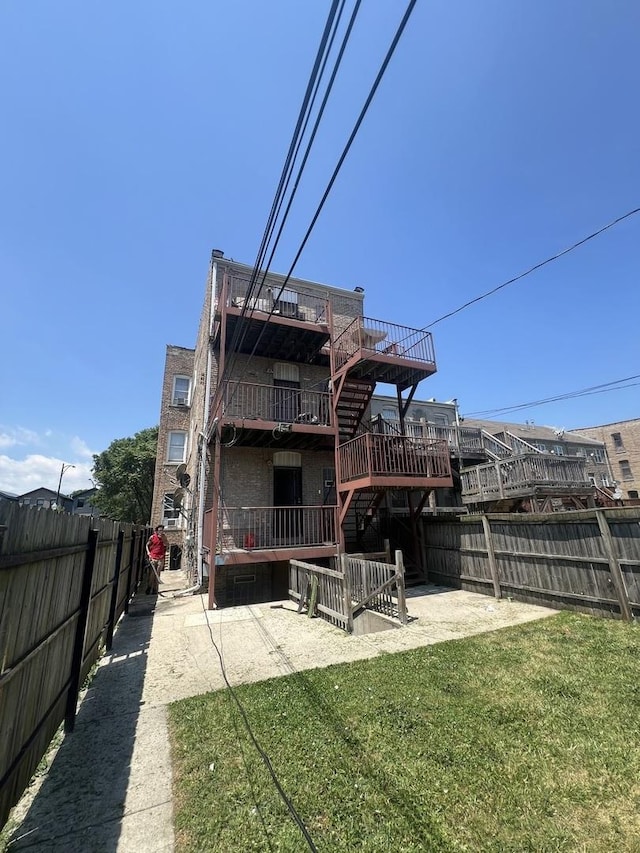 rear view of house featuring a patio area, a yard, a fenced backyard, stairs, and a deck