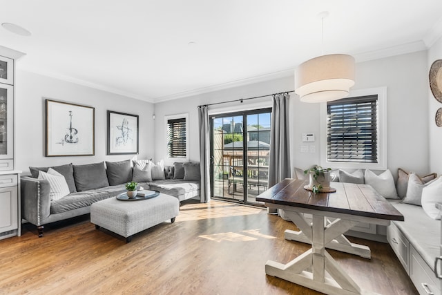 living room featuring ornamental molding, breakfast area, and light wood-type flooring