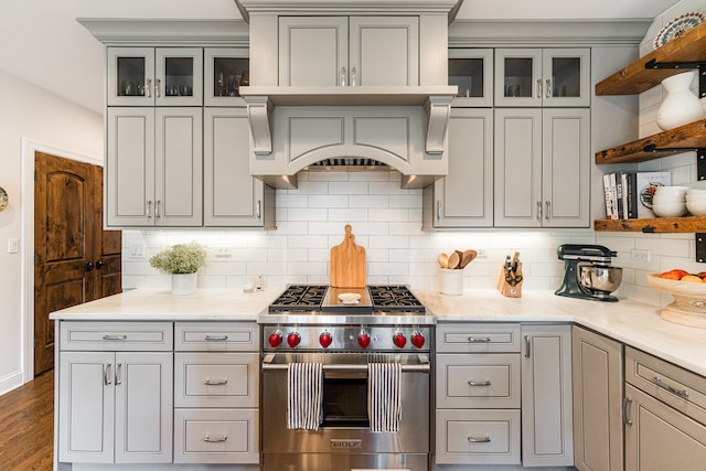 kitchen with light stone counters, decorative backsplash, premium stove, and dark hardwood / wood-style floors