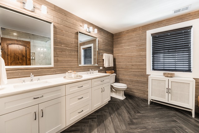 bathroom featuring vanity, toilet, wooden walls, and parquet floors