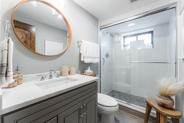 bathroom featuring vanity, toilet, hardwood / wood-style flooring, and an enclosed shower