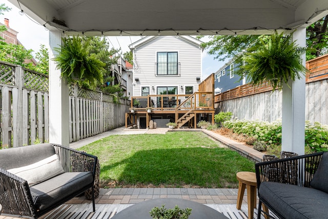 rear view of house featuring a wooden deck, a patio, and a lawn