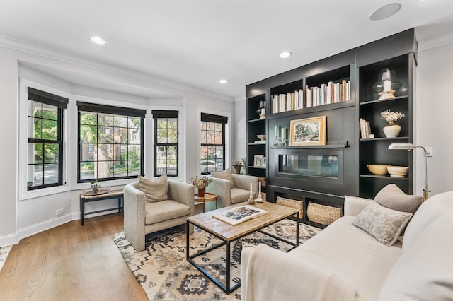 living area with ornamental molding, built in shelves, and hardwood / wood-style floors