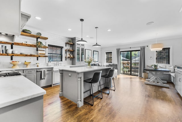 kitchen with stainless steel dishwasher, a breakfast bar area, hanging light fixtures, and gray cabinetry