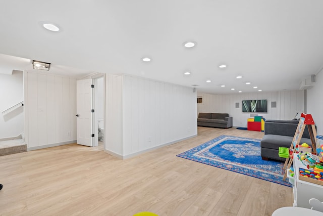 game room featuring light hardwood / wood-style floors and wood walls