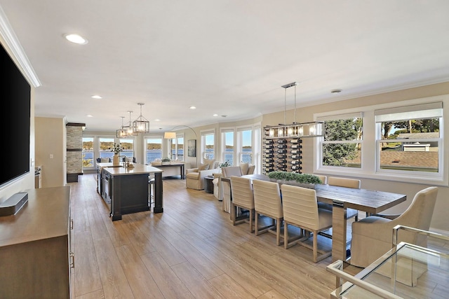 dining area featuring light hardwood / wood-style floors, ornamental molding, and plenty of natural light