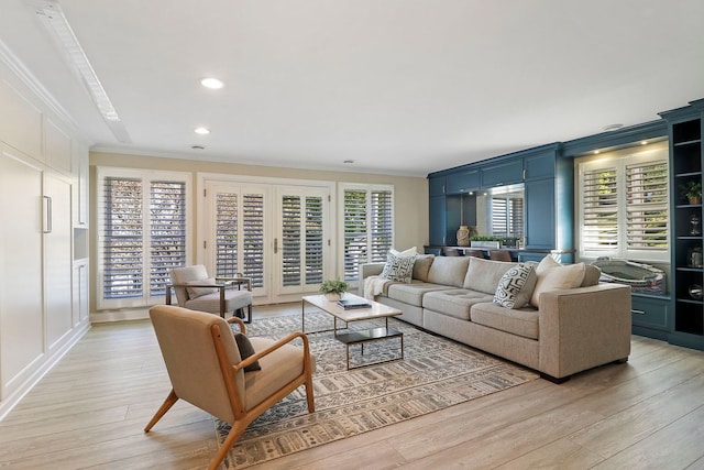 living room featuring french doors, a healthy amount of sunlight, ornamental molding, and light hardwood / wood-style flooring