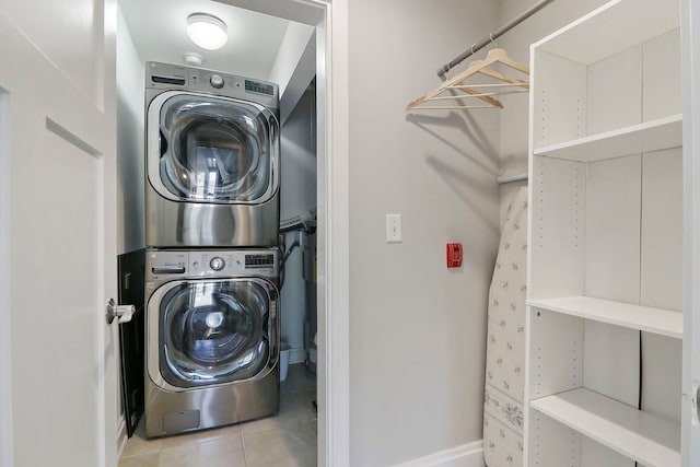 clothes washing area with stacked washer / drying machine and light tile patterned floors