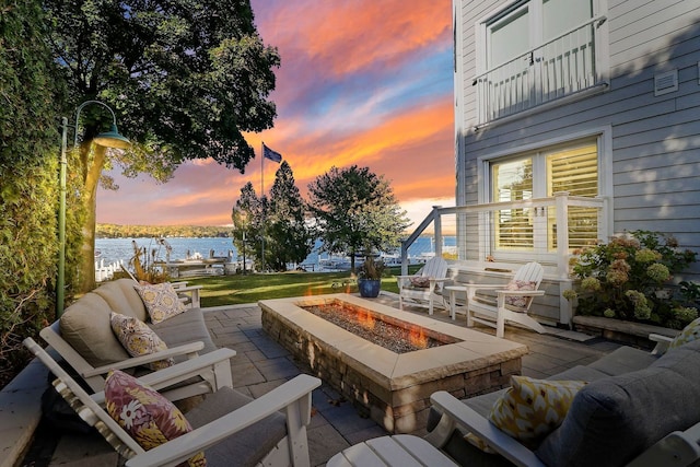 patio terrace at dusk with a water view and an outdoor living space with a fire pit