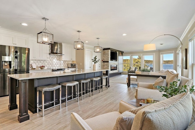 living room featuring light hardwood / wood-style floors, ornamental molding, sink, and a fireplace