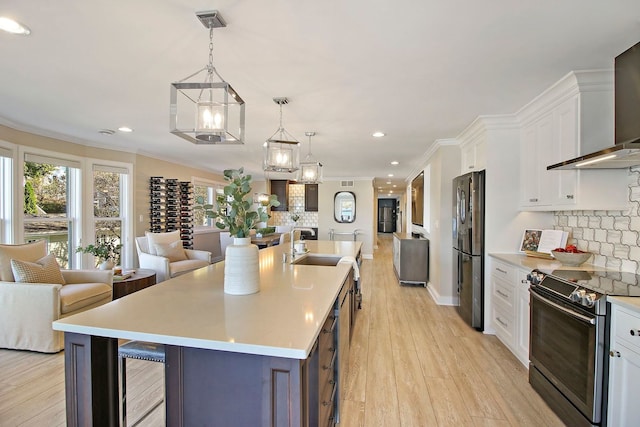 kitchen featuring light hardwood / wood-style flooring, white cabinets, stainless steel appliances, and a large island with sink