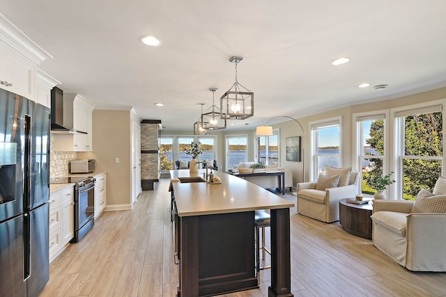 kitchen featuring wall chimney exhaust hood, stainless steel fridge, black electric range oven, and white cabinetry