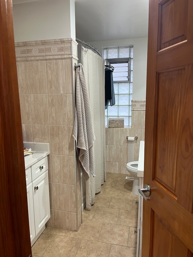 bathroom with vanity, tile patterned floors, walk in shower, tile walls, and toilet