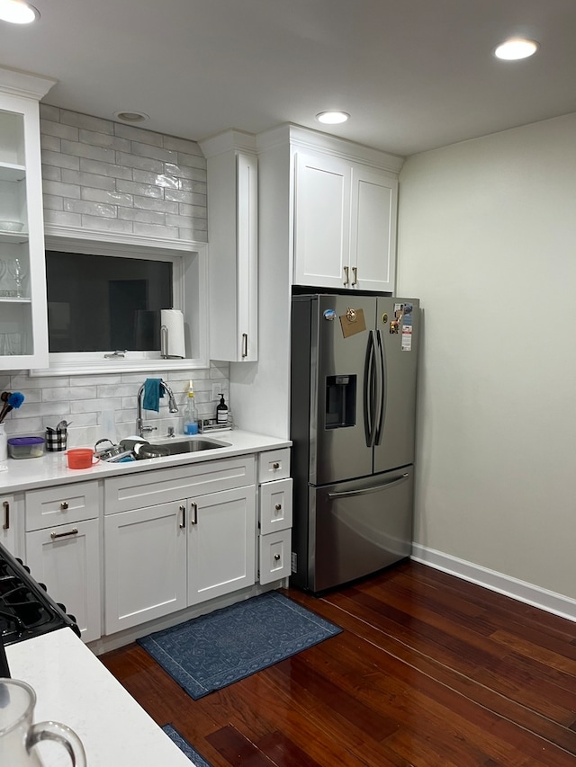 kitchen with dark wood-type flooring, sink, stainless steel fridge, and white cabinetry