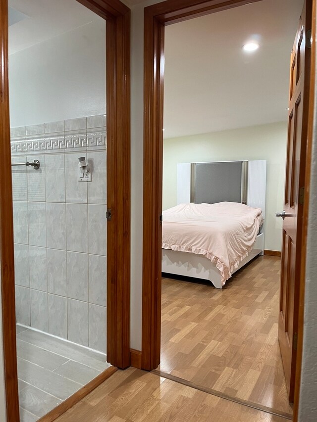 unfurnished bedroom with hardwood / wood-style floors and tile walls