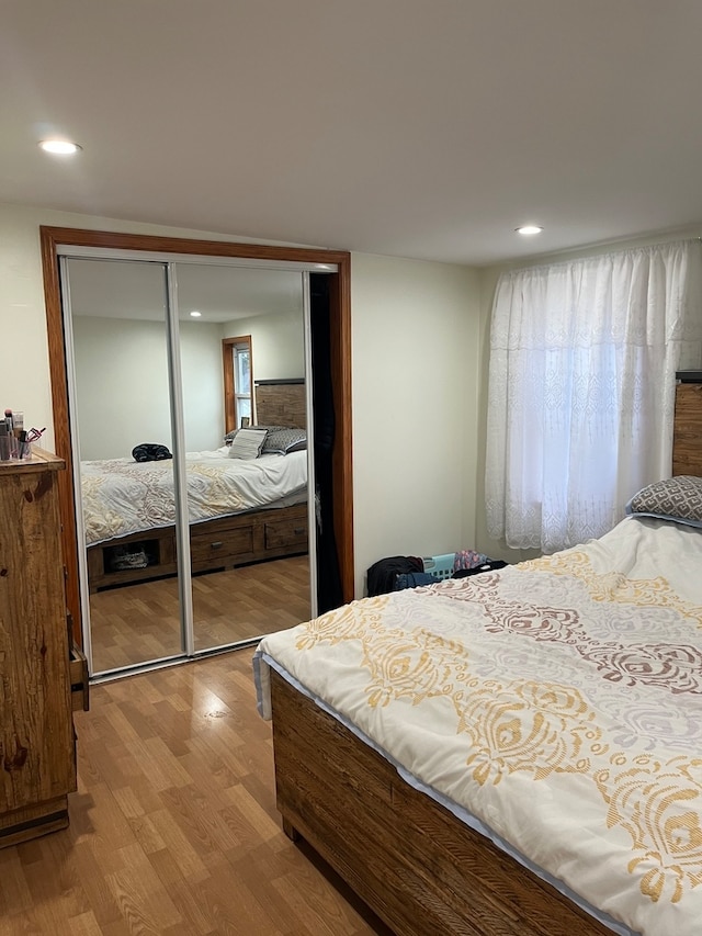 bedroom with multiple windows, a closet, and light hardwood / wood-style floors