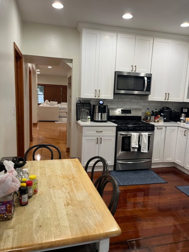 kitchen featuring tasteful backsplash, white cabinets, appliances with stainless steel finishes, and dark hardwood / wood-style flooring