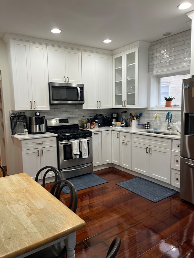 kitchen with appliances with stainless steel finishes, sink, dark hardwood / wood-style flooring, and white cabinetry