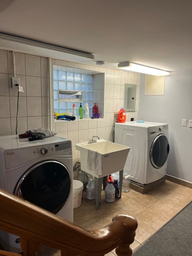 laundry room with sink, tile walls, electric panel, washing machine and dryer, and light tile patterned floors