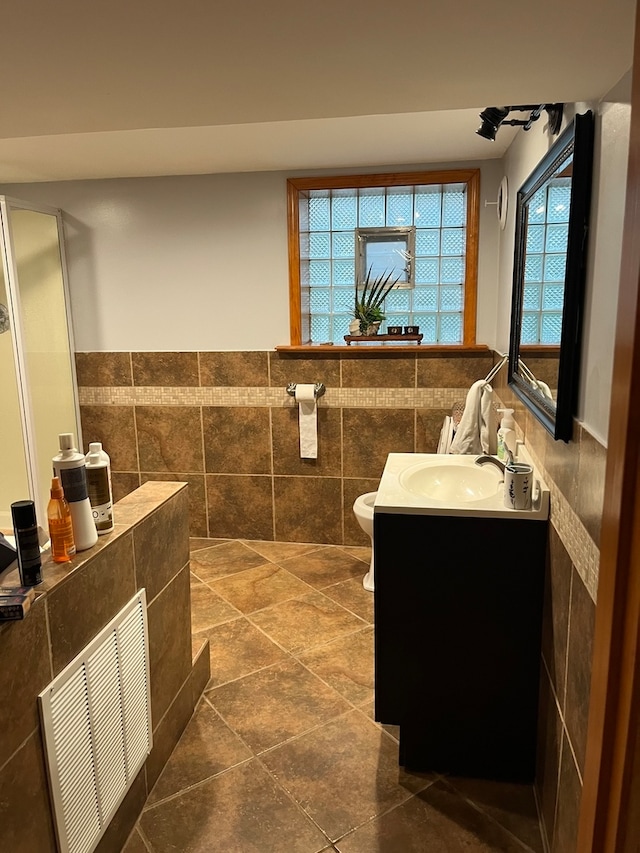 bathroom featuring vanity, tile patterned flooring, toilet, and tile walls