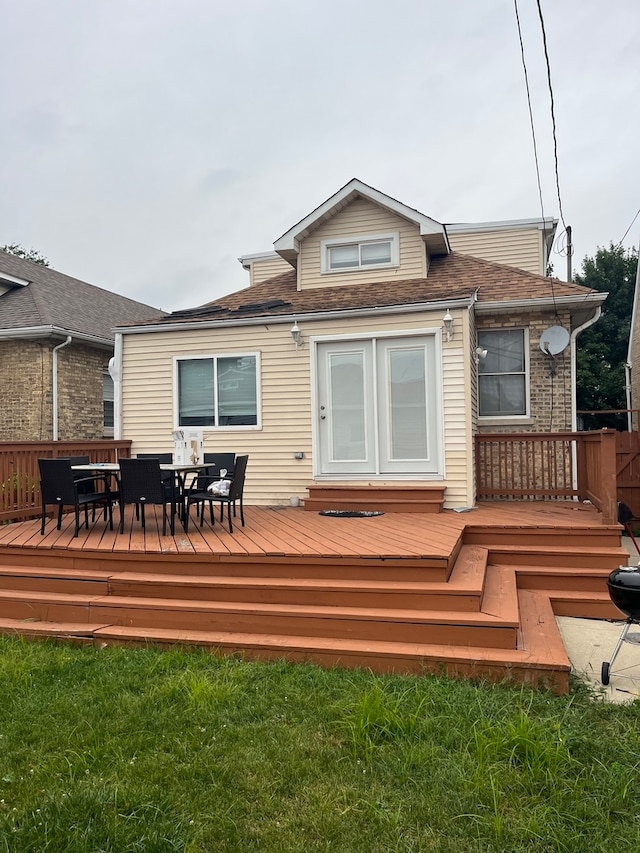 rear view of property featuring a wooden deck and a lawn