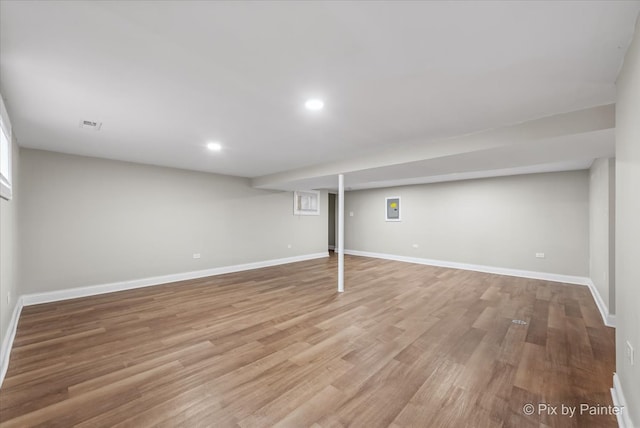 basement with light hardwood / wood-style flooring and electric panel