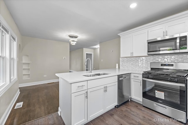 kitchen featuring appliances with stainless steel finishes, kitchen peninsula, white cabinetry, and sink