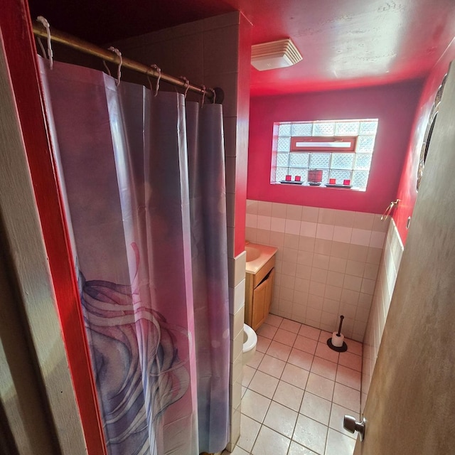 bathroom featuring toilet, tile patterned flooring, curtained shower, tile walls, and vanity