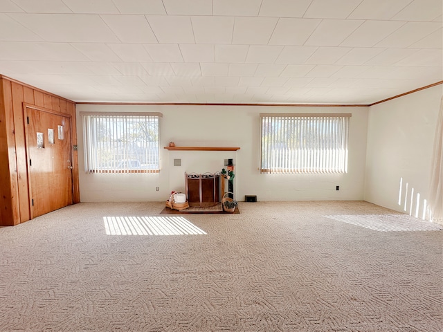 unfurnished living room with crown molding, carpet flooring, and a wealth of natural light