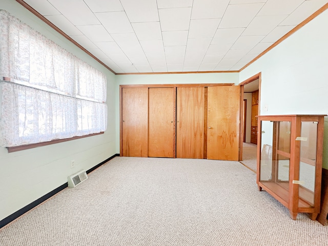 unfurnished bedroom with a closet, light carpet, and ornamental molding