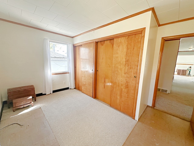 unfurnished bedroom with light carpet, a closet, and crown molding