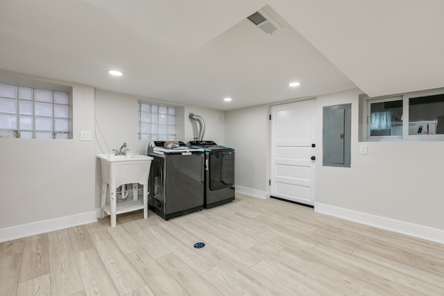 laundry room featuring independent washer and dryer, electric panel, and light hardwood / wood-style flooring