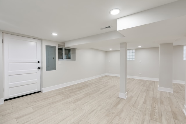 basement featuring electric panel and light wood-type flooring