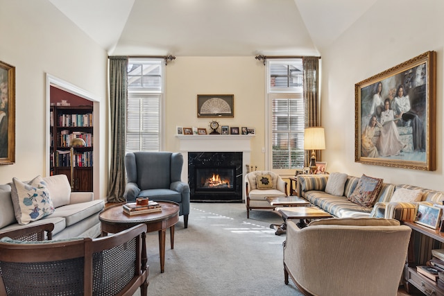 living room with a fireplace, vaulted ceiling, and light colored carpet