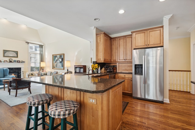 kitchen with kitchen peninsula, stainless steel fridge, a breakfast bar, dark hardwood / wood-style floors, and crown molding